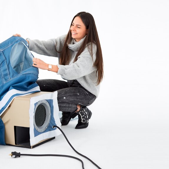 A woman is inserting the 220V permanent fan through the appropriate opening in the inflatable advertising media. 