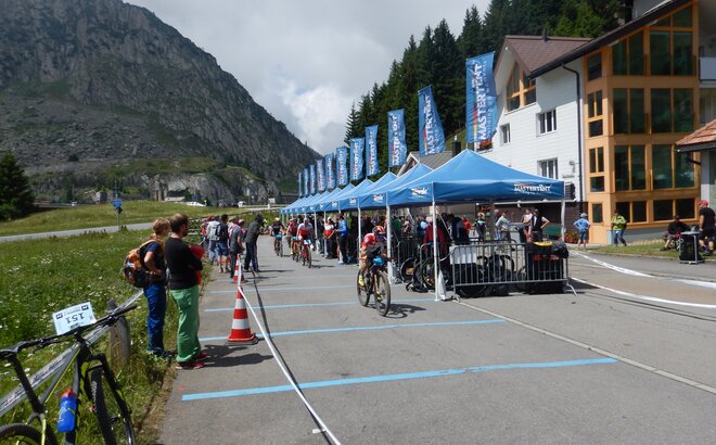 Die teilnehmenden Radfahrer fahren an den Zuschauern und blauen MASTERTENT Faltpavillons vorbei.