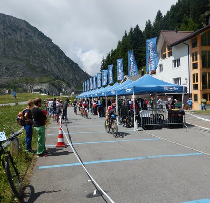 The participating cyclists are passing the spectators and blue gazebos MASTERTENT gazebo next to the race tracks