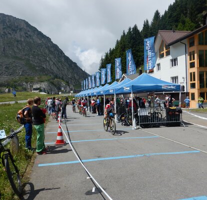 Die teilnehmenden Radfahrer fahren an den Zuschauern und blauen MASTERTENT Faltpavillons vorbei.