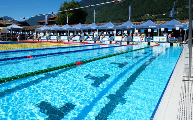 Eine Schwimmerin, mit einer weißen Badehaube und schwarzen Badeanzug, schwimmt Richtung Ziel.