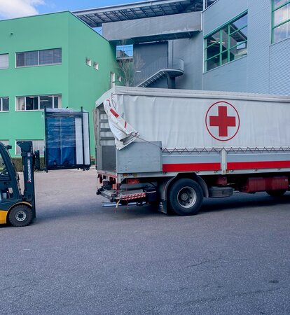 Die Faltpavillons werden gerade mit einem Gabelstapler in den LKW des Roten Kreuzs geladen.