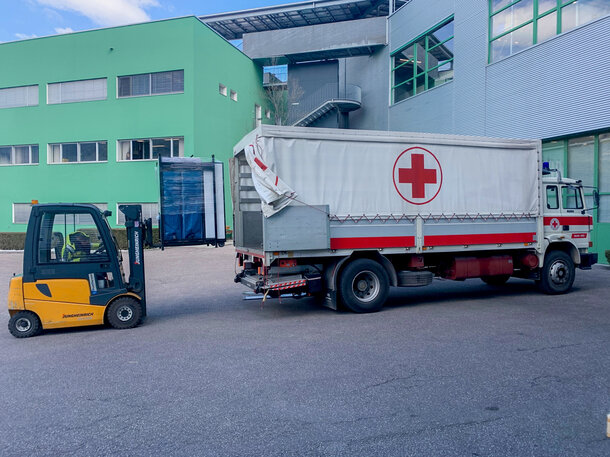 Die Faltpavillons werden gerade mit einem Gabelstapler in den LKW des Roten Kreuzs geladen.