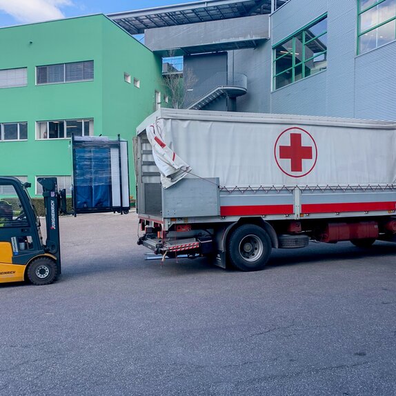 Die Faltpavillons werden gerade mit einem Gabelstapler in den LKW des Roten Kreuzs geladen.