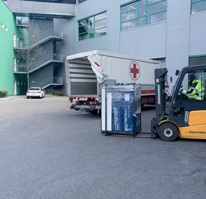 Der Gabelstapler fährt die Faltzelte zum LKW des Roten Kreuz.