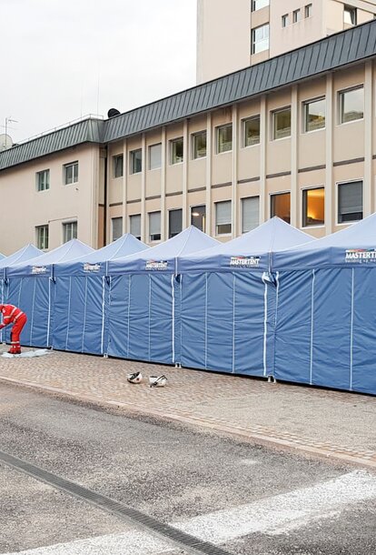 Blaue Faltpavillons von Mastertent bilden einen langen Korridor vor dem Krankenhaus Bozen zur Bekämpfung des Coronavirus.