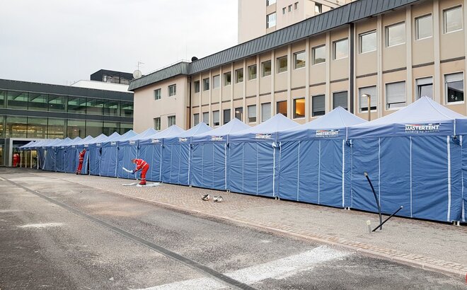 Un lungo corridoio di gazebo pieghevoli davanti all'ospedale di Bolzano. Aiuto nella battaglia contro il coronavirus.