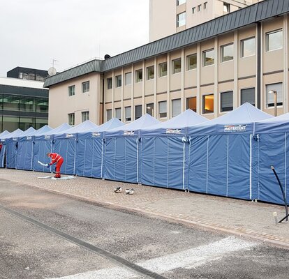 Blaue Faltpavillons von Mastertent bilden einen langen Korridor vor dem Krankenhaus Bozen zur Bekämpfung des Coronavirus.