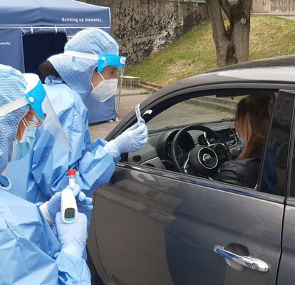 At the drive-in test station, two paramedics take smears from a female driver.