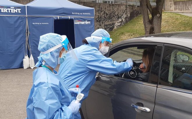 Zwei Sanitäterinnen nehmen von einer Autofahrerin Testabstriche. Dahinter steht ein blaues Mastertent Faltzelt. 