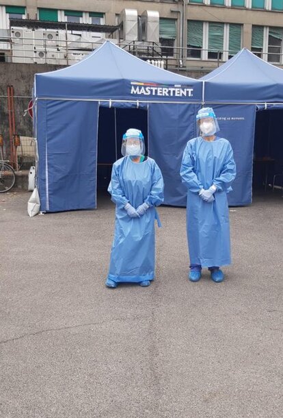 2 Sanitäterinnen, 1 Arzt und ein Koordinator stehen vor einem blauen Mastertent Faltzelt. 