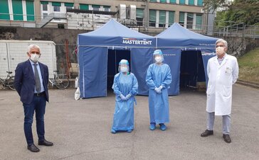 2 paramedics, 1 doctor and a coordinator stand in front of a blue Mastertent folding tent. 