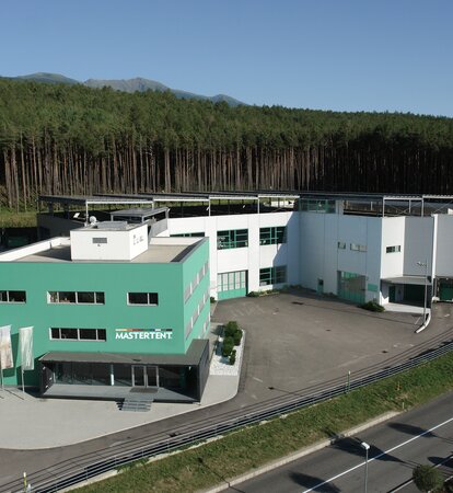 The Mastertent Building is green. In the background is a forest. 