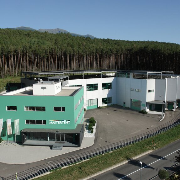 The Mastertent Building is green. In the background is a forest. 