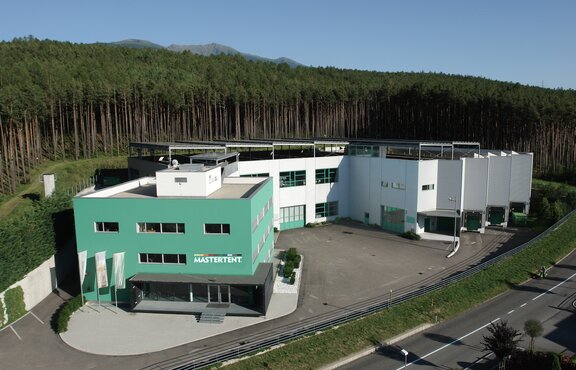 The Mastertent Building is green. In the background is a forest. 