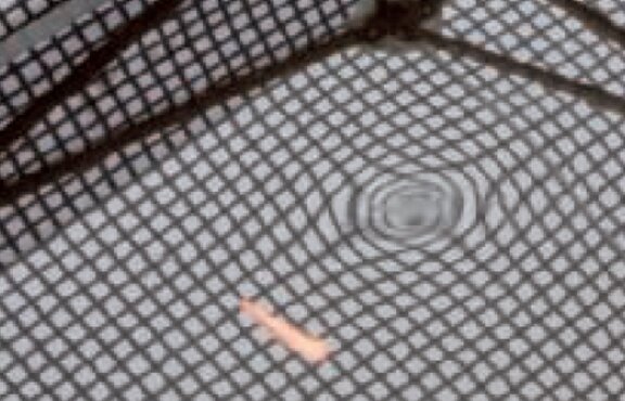 Schwarze Oberfläche des Autos mit einer Delle in der Mitte. Das Muster zeigt die Delle.