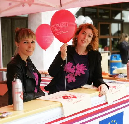 Cora Cavicchi con una collaboratrice sotto il gazebo pieghevole ad un evento. In mano tiene un palloncino. 