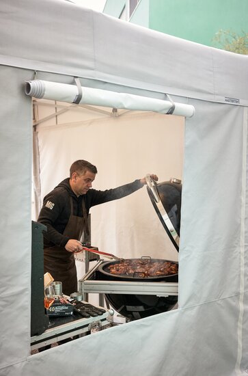 Uomo griglia sotto un gazebo cucna Mastertent 4,5x3 m con pareti laterali con fineste