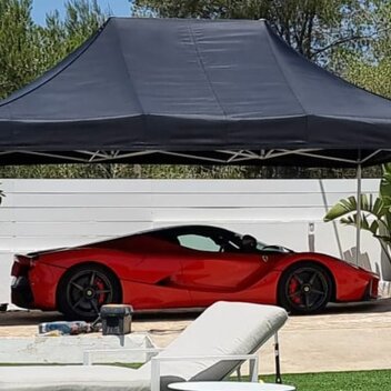 Black 4.5x3m Mastertent car gazebo with red Ferrari on luxury garden with pool