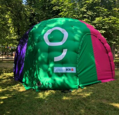 A colourful inflatable tent is located in the meadow. It is printed with the logo of George, BCR. 