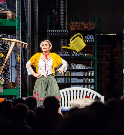 The actress Ingrid Maria Lechner is standing on the stage and performing a drama with different utensils.