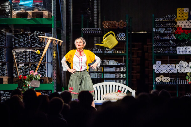 The actress Ingrid Maria Lechner is standing on the stage and performing a drama with different utensils.