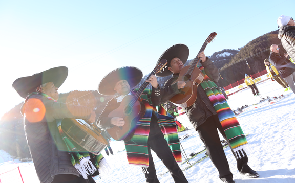 Die Musiker bei den mexikanischen Meisterschaften singen und spielen Gitarre im Schnee. Es strahlt die Sonne.