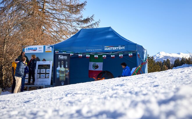 Blauer Faltpavillon steht am Pistenrand eines Skirennens.