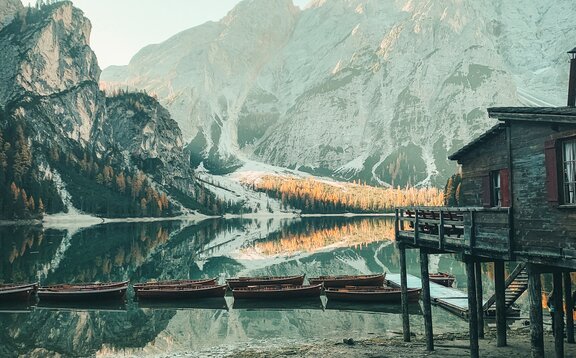 Braies Wild Lake with the cottage and its boats. Behind it mountains are glowing.