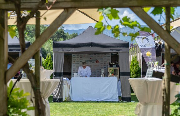 Der Koch steht unter dem Faltpavillon mit Lodenstoffüberzug. | © Martin Corradini