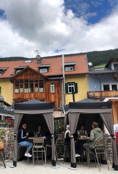 Two loden tents from Mastertent are situated on the terrace of a bistro. They serve as catering tents. Customers are enjoying der drinks underneath. 