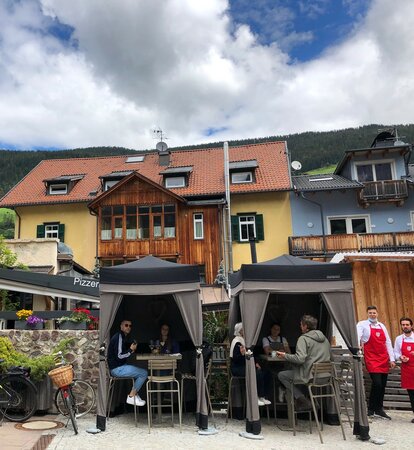 Two loden tents from Mastertent are situated on the terrace of a bistro. They serve as catering tents. Customers are enjoying der drinks underneath. 