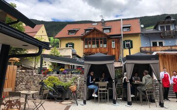 Two loden tents from Mastertent are situated on the terrace of a bistro. They serve as catering tents. Customers are enjoying der drinks underneath. 