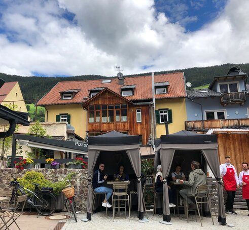 Two loden tents from Mastertent are situated on the terrace of a bistro. They serve as catering tents. Customers are enjoying der drinks underneath. 