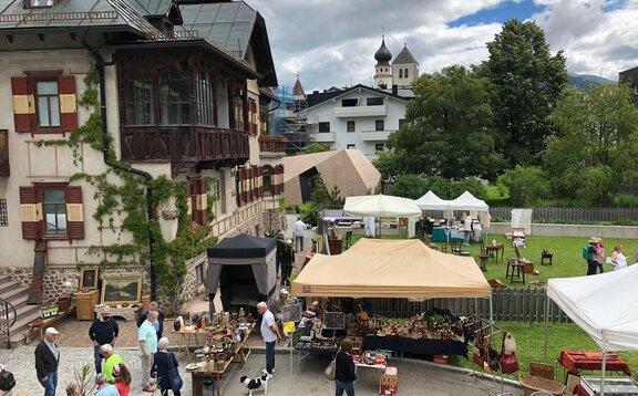 Gazebo pieghevole sul mercato dell'arte Un gazebo pieghevole in beige delle dimensioni 6x4m e un gazebo pieghevole con copertura in loden delle dimensioni 1,5x1,5m da Mastertent si trovano sulla piazza del mercato di un mercato dell'arte.