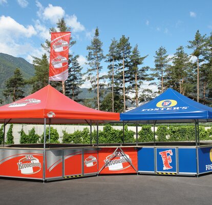 Una chiosco personalizzato della ditta Kronenbourg è collegato ad un stand personalizzato della ditta Fosters.