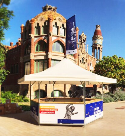 Ein 6-eckiger Getränkestand in Barcelona mit schlichtem Dach und bunt bedruckten Paneelen.