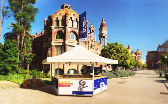 Ein 6-eckiger Getränkestand in Barcelona mit schlichtem Dach und bunt bedruckten Paneelen.