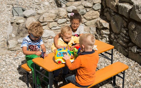 4 children are playing with their playing tools on the little table and bench set called Bambini. 