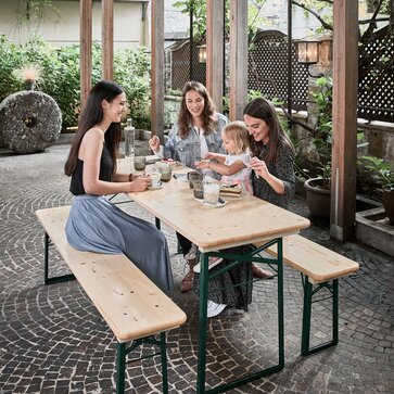 Le tre donne e la bambina si siedono sul tavolo di birra compatto e naturale e bevono un caffè.