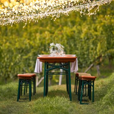 The classic beer tent set is decorated with white-green flower bouquets and stands amidst vines under hanging fairy lights.