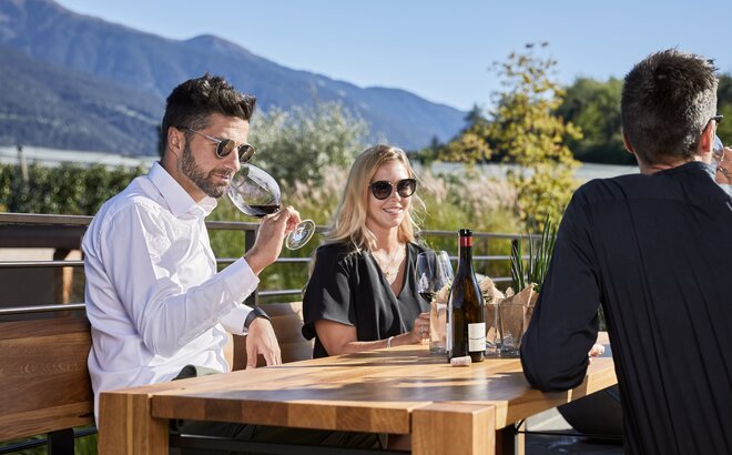 Quattro persone sono sedute sul set Lago. Il uomo in camicia bianca beve il vino. 