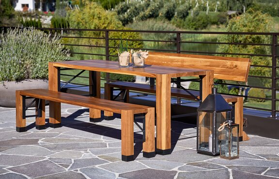 The modern Lago beer tent set is located on the terrace in front of a lake. The beer tent set is decorated with flower vases and a latern.