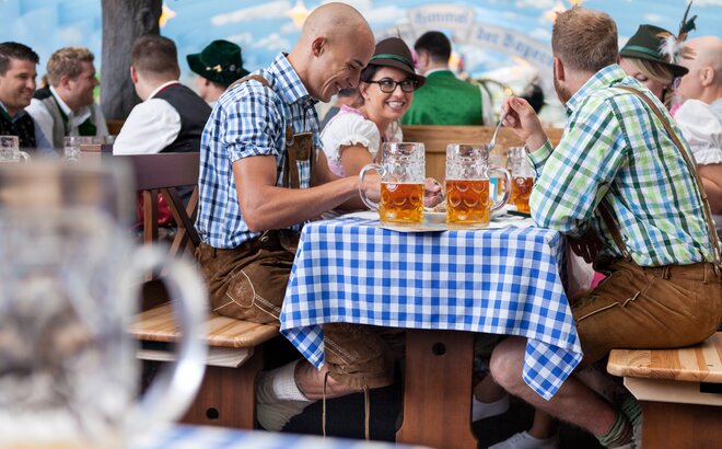 Oktoberfest guests sitting on special table and bench sets in the Hacker Pschorr tent and drinking beer. 