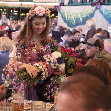 Souvenir seller with roses, hair wreaths and heart-shaped pins at the Oktoberfest amongst many beer tent sets