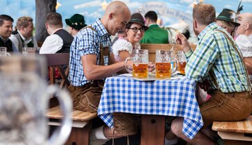 Oktoberfestbesucher sitzen auf den Sondergarnituren im Hacker Pschorr Festzelt und trinken ein Bier.