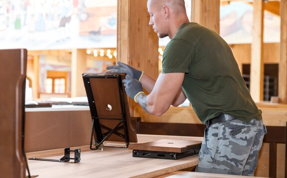 Mann stellt die maßgeschneiderten Bierbänke im Hacker Pschorr Festzelt auf. Es handelt sich um Sondergarnituren für das Oktoberfest.