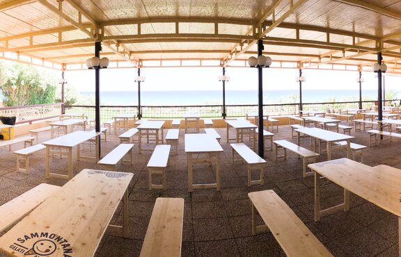 Naturfarbene Rusticagarnituren auf der Terrasse im Lido San Lorenzo. Dahinter sieht man den Strand und das Meer.
