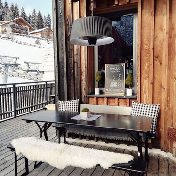 Die schwarze Bierzeltgarnitur steht auf der Dachterrasse vom Après Ski Lokal Gassl. Die Biertischgarnitur in schwarz ist dekoriert mit Lammfellen und Kissen.