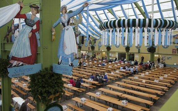 Detailansicht der Markierung der Sitzreihen im Ochsenbraterei Festzelt auf dem Münchner Oktoberfest. Dahinter stehen Oktoberfestgarnituren.